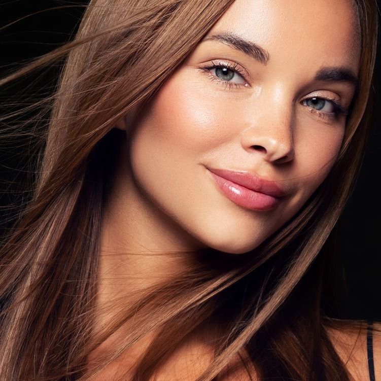 Smiling woman with flowing hair against black background.