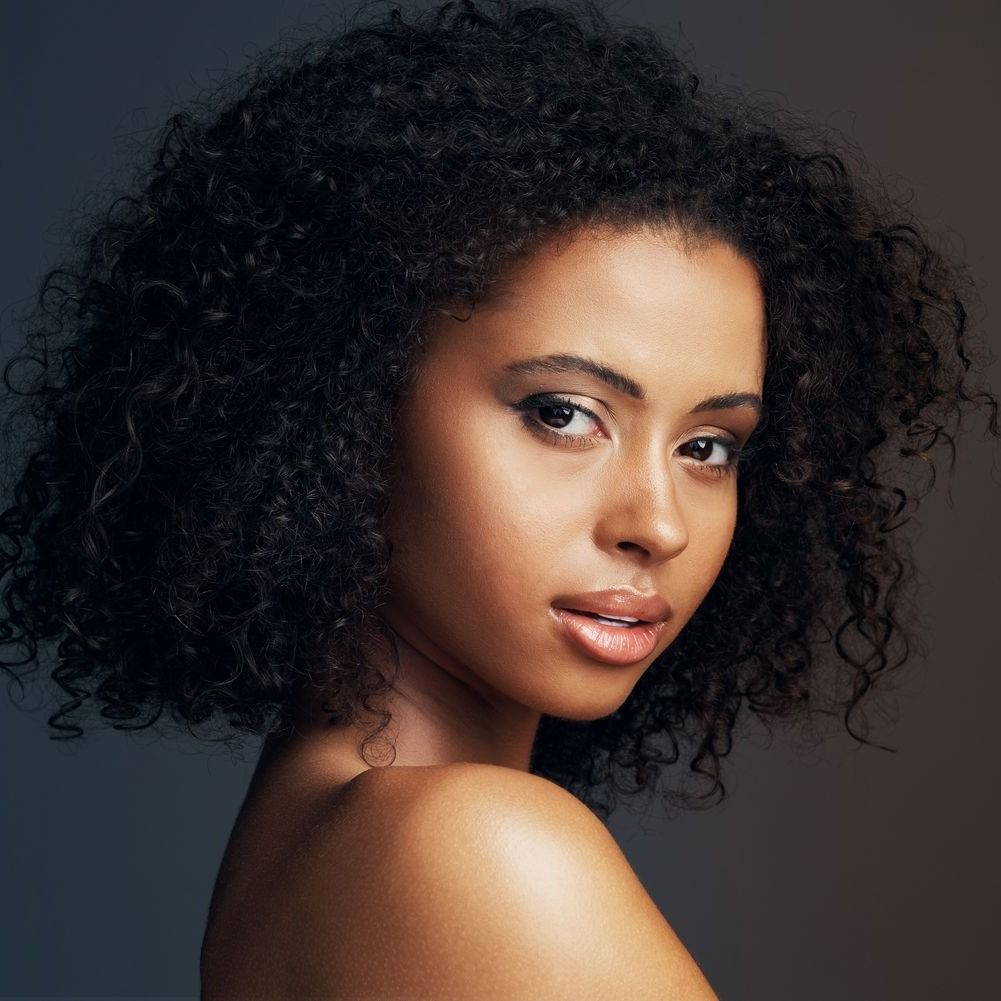 Woman with curly hair against a dark background.