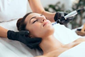 Relaxed young woman receiving a microneedling treatment to treat fine lines and wrinkles in a spa-like room