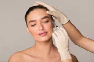 Close up of a woman receiving a Botox injection around her eyes from her aesthetic nursing injector