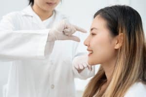 Young woman having her nose examined by her provider for liquid rhinoplasty treatment.