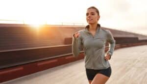 Woman smiling and jogging outside as a result of increased energy from vitamin B12 injections.